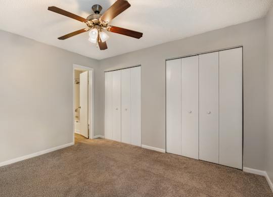 A room with a ceiling fan and three white doors.