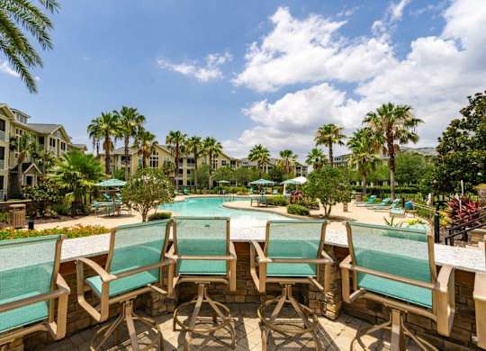 Pool surrounded by wooden chairs and palm trees at Bridges at Crosstown in Tampa, FL