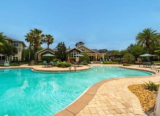Swimming pool surrounded by palm trees and lounge chairs at Bridges at Crosstown in Tampa, FL