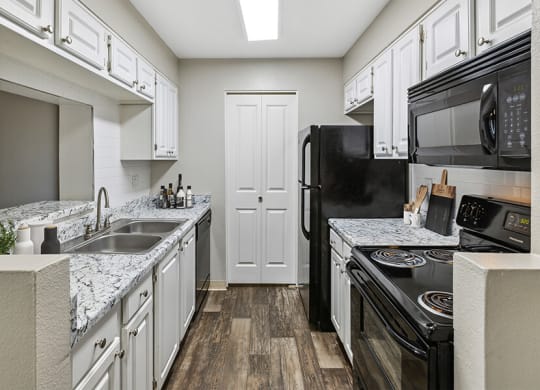 a kitchen with white cabinets and black appliances