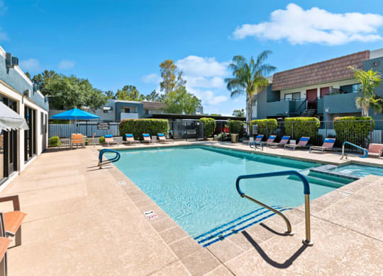a swimming pool with lounge chairs and umbrellas in front of a building