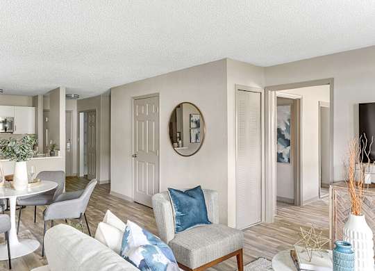 Model Living Room with Wood-Style Flooring and View of Kitchen at Mirage on Kernan Apartments located in Jacksonville, FL.