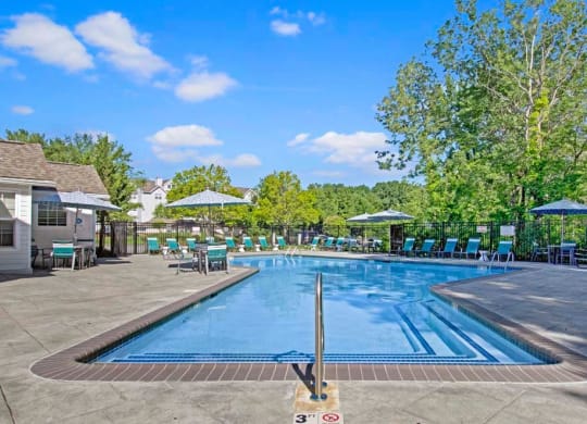 a resort style pool with lounge chairs and umbrellas