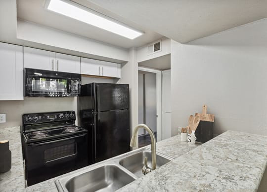 a kitchen with granite countertops and black appliances