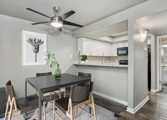 a dining area with a table and chairs and a ceiling fan