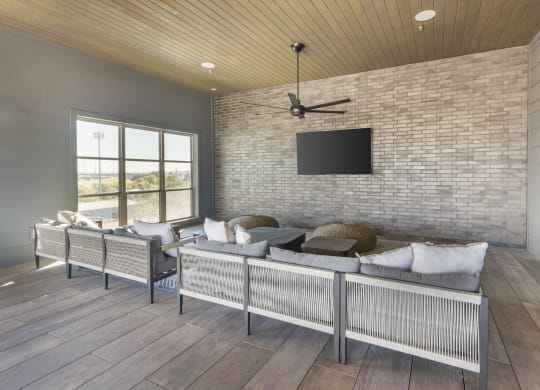 a living room with a couch and a tv on a brick wall