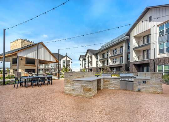 A courtyard with a stone wall and a grill in the middle.