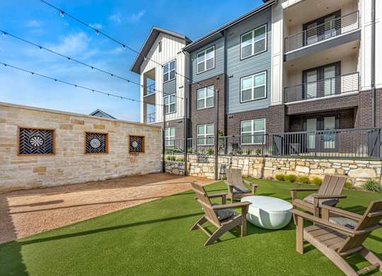 A sunny day at a modern apartment complex with a stone wall and a lawn.