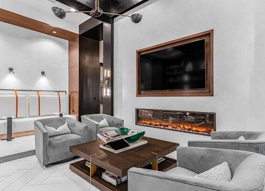 Community Clubhouse with Lounge Furniture, TV and Fireplace at Ovation at Galatyn Park Apartments located in Richardson, TX.