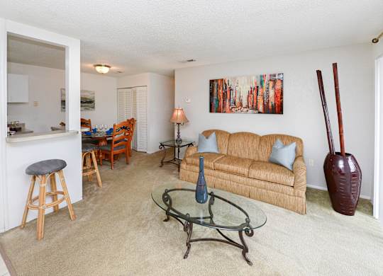 A living room with a couch, a chair, a table, and a painting on the wall.