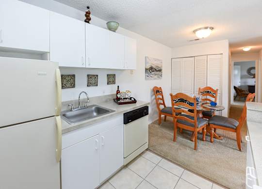 A kitchen with white cabinets and a white refrigerator.