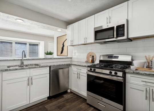 Model apartment kitchen with white cabinets and stainless steel appliances