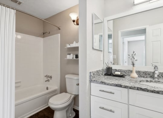Model apartment bathroom with a shower toilet and sink and a mirror