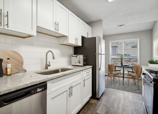 Model apartment kitchen with white cabinets and a sink and a refrigerator