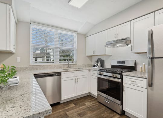 Model apartment kitchen with white cabinets and stainless steel appliances
