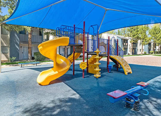 Community Playground with a Slide and Blue Canopy at Solano Springs Apartments in Tucson, AZ.
