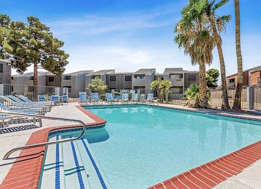 a swimming pool with chairs and palm trees