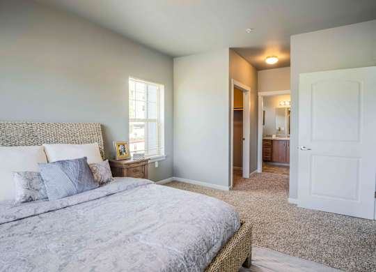 A bedroom with a bed, nightstand, and a window.