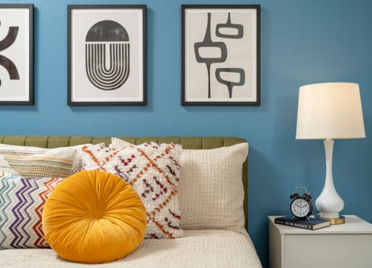 a bedroom with a blue wall and three pieces of art above the bed