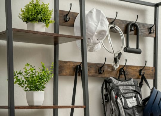 a metal shelving unit with hooks and a backpack on it and plants on the shelves