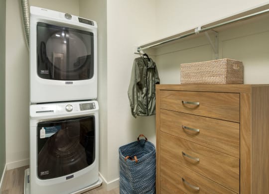 a washer and dryer sit next to a dresser in a laundry room