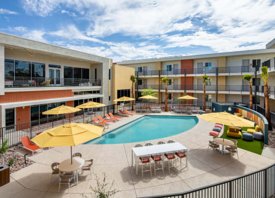 a swimming pool with yellow umbrellas and red and white chairs