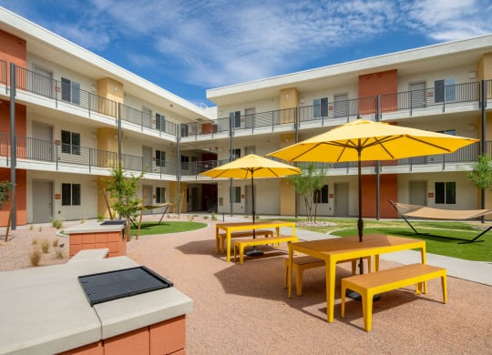 a courtyard with yellow tables and yellow umbrellas