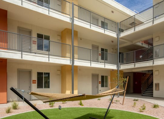 a hammock sits in the courtyard of an apartment building