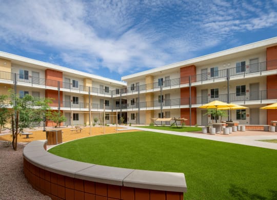 a courtyard with a grassy area and a lawn in front of an apartment building