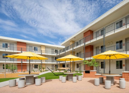 a courtyard with tables and chairs and yellow umbrellas