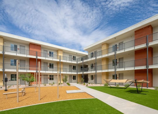a courtyard with a picnic table and benches in front of an apartment building