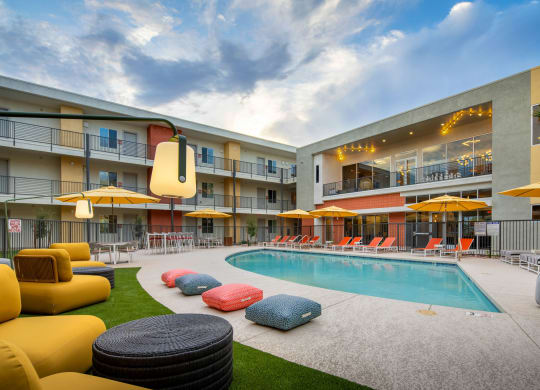 a swimming pool with lounge chairs and umbrellas in front of a building