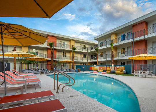 a swimming pool with yellow umbrellas and red and white lounge chairs