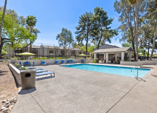 a swimming pool with lounge chairs and umbrellas in front of a building