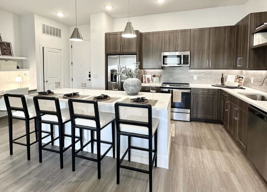 a kitchen with a large island with four chairs