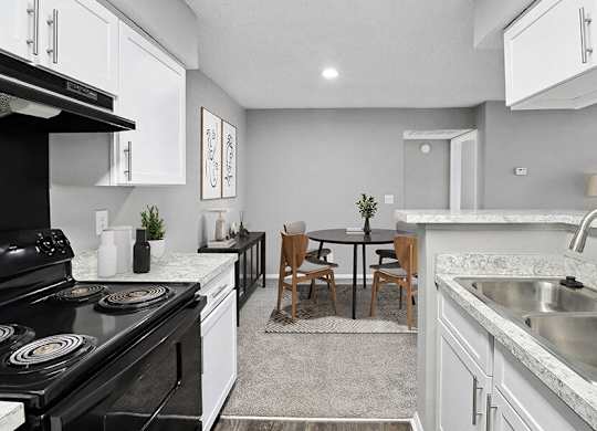 Model Kitchen with White Cabinets, Wood-Style Flooring and View of Dining Room at Abbington Heights Apartments in Antioch, TN.