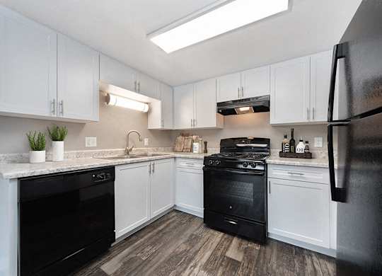 Model Kitchen with White Cabinets and Wood-Style Flooring at Bridges at 9 Mile Station Apartments in Denver, CO.