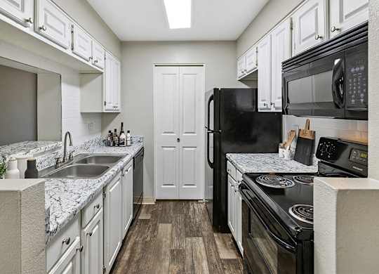 a kitchen with white cabinets and black appliances
