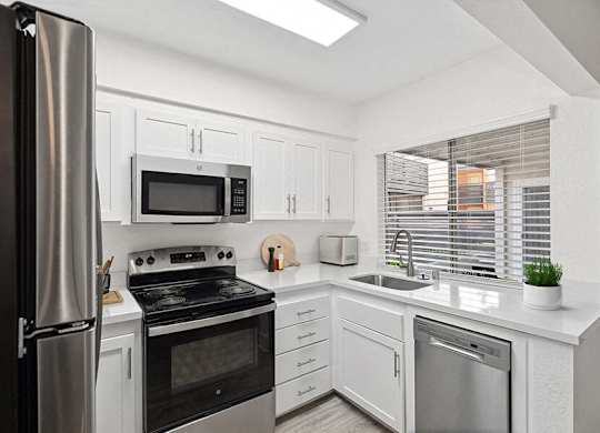 Model Kitchen with White Cabinets and Wood-Style Flooring at Horizon Apartments located in Santa Ana, CA.