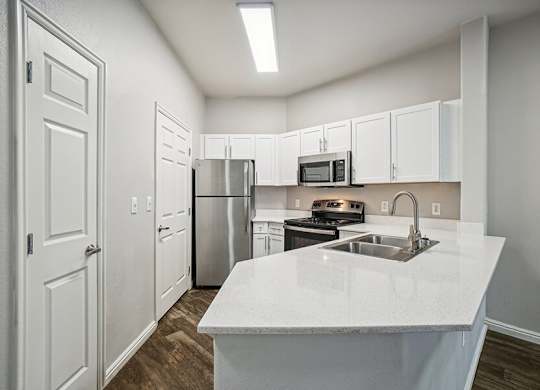 Model Kitchen with Wood-Style Flooring, White Cabinets, and Stainless-Steel Appliances at Altitude on Fifth Apartments located in Salt Lake City, UT.
