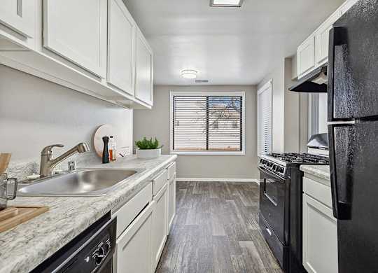 Silver Spring, MD Apartments for Rent - Spring Parc - Updated Galley Kitchen With White Cabinets, Marble Look Counters, Gas Range, Black Refrigerator, And Wood Style Flooring