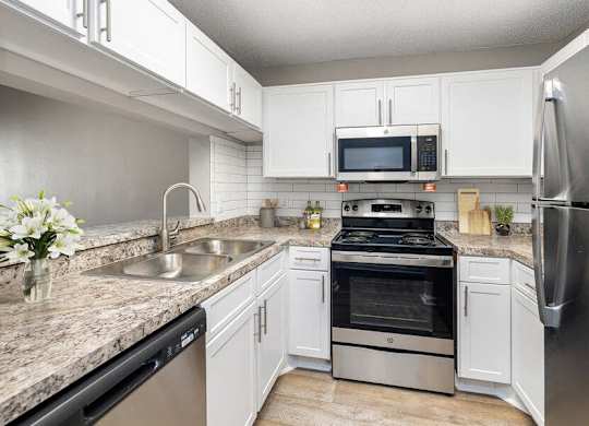 Pet-Friendly Apartments in Westside Jacksonville, FL - Westland Park - A Kitchen Features White Cabinets, Granite Countertops, Stainless Steel Appliances, And A Double Sink.