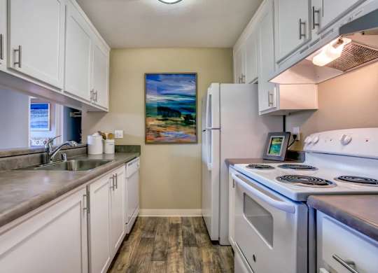 A kitchen with white cabinets and a painting on the wall.