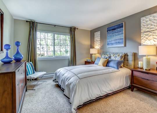 A bedroom with a large bed and a window with curtains.