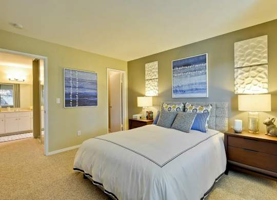 A bedroom with a large bed and a nightstand with a lamp.