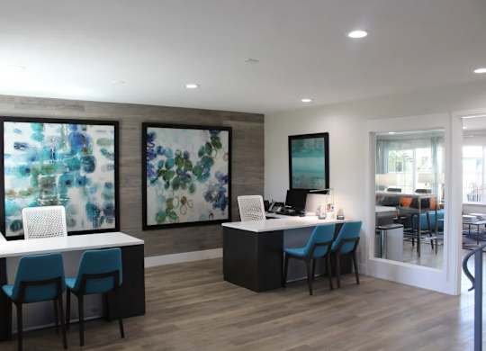 A modern office space with blue chairs and two abstract paintings on the wall.