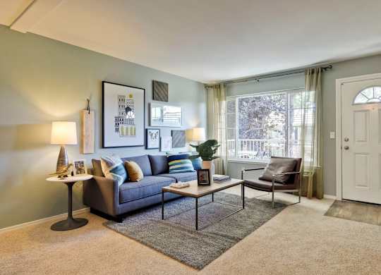 A living room with a grey couch, a coffee table, and a lamp.