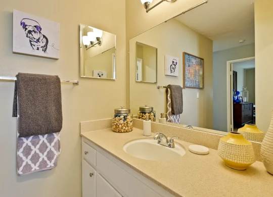 A bathroom with a white counter top and a brown towel hanging on the door.