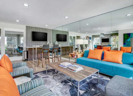 A living room with a blue couch and orange pillows.