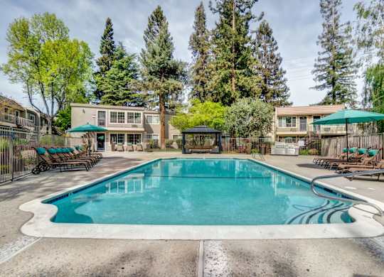 A swimming pool surrounded by trees and a building in the background.